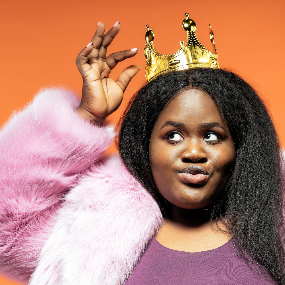 Woman wearing a gold crown and pink fur coat against an orange background