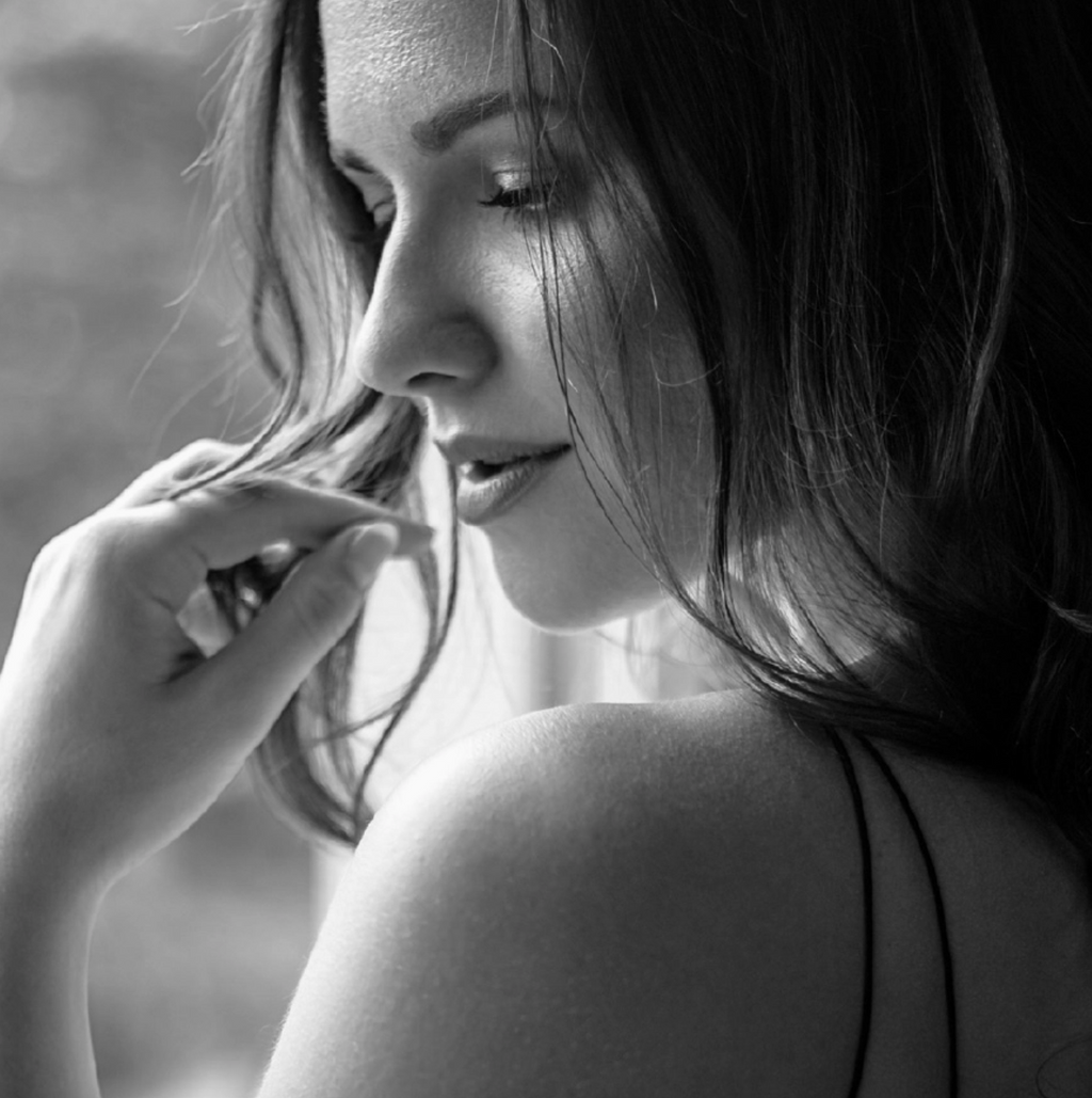 Black and white close-up of a woman with her hand near her face.